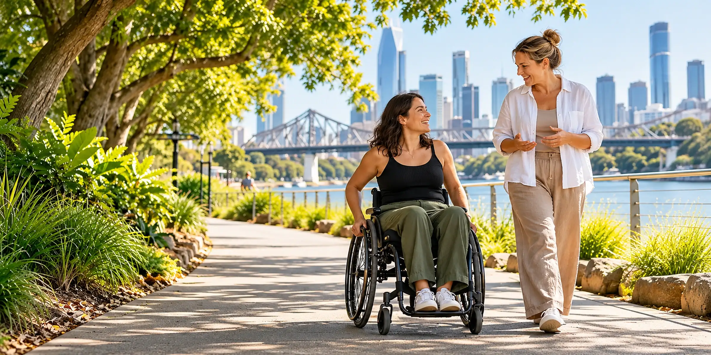 A participant and support worker walking and talking along a riverside path